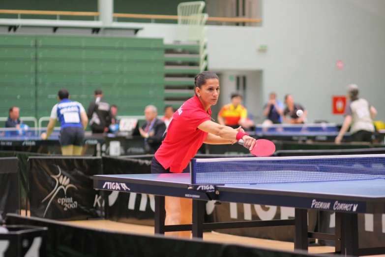 the man in the red shirt is playing ping pong