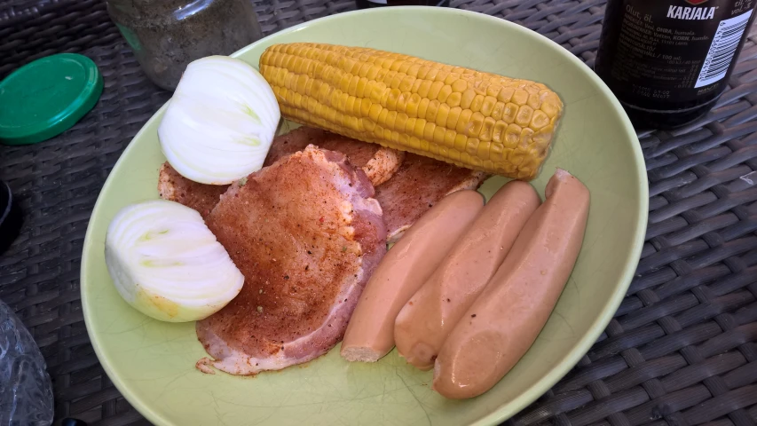 a plate of food that includes corn, meat, and  dogs