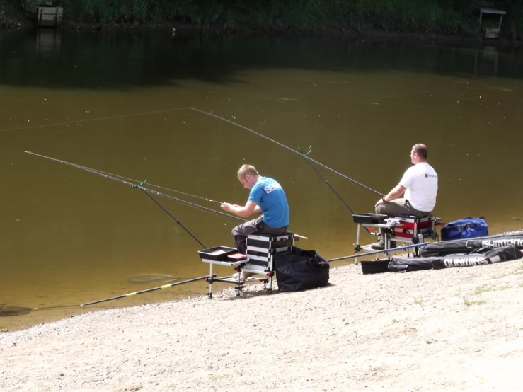 two men fishing from their motor bikes on a lake shore