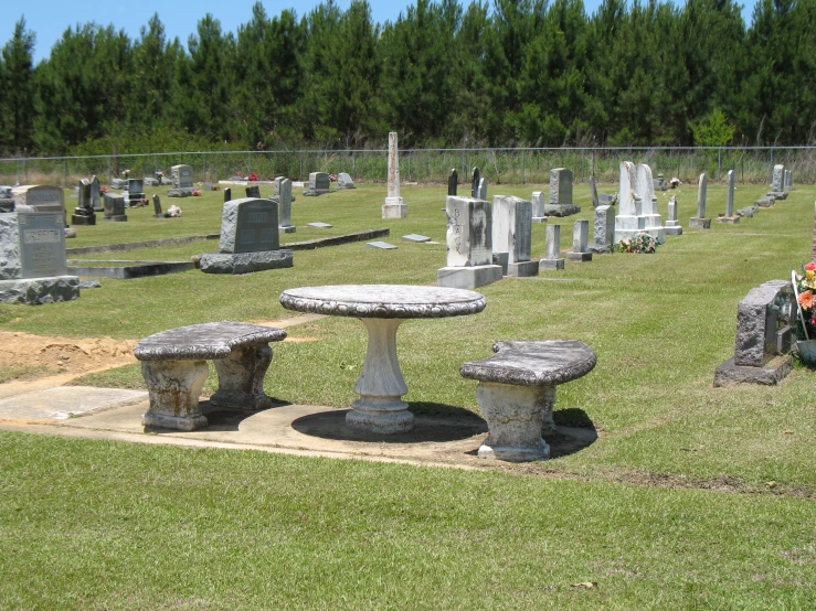 a cemetery with three concrete benches in the grass