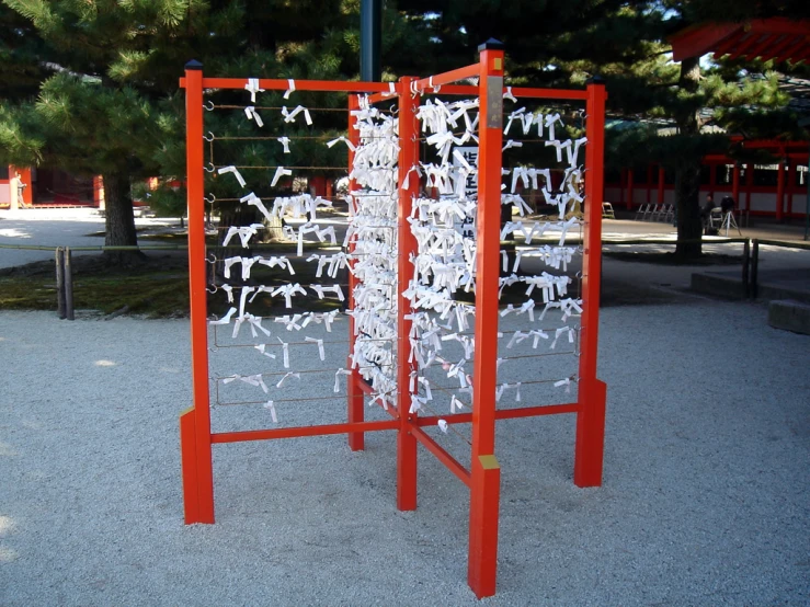 red wooden structure with multiple pieces of cloth attached to it