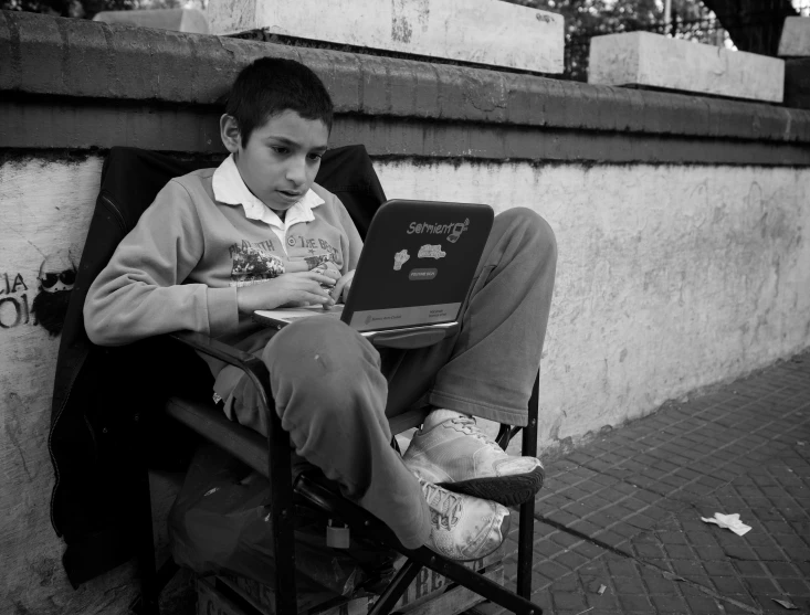 a  sitting in an outdoor chair on his laptop