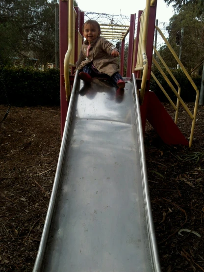 a toddler plays on the slide that is located at the playground
