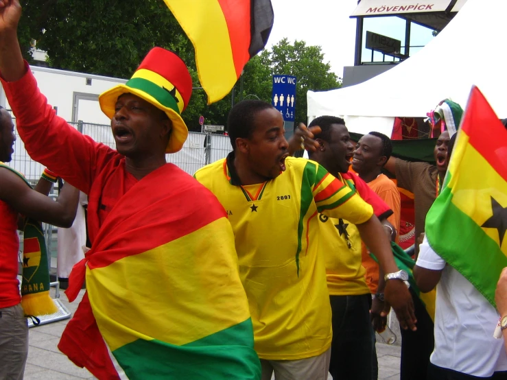 a group of men dancing around in rasta colors