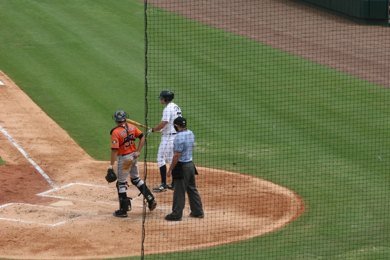 baseball players stand on the field talking to an umpire