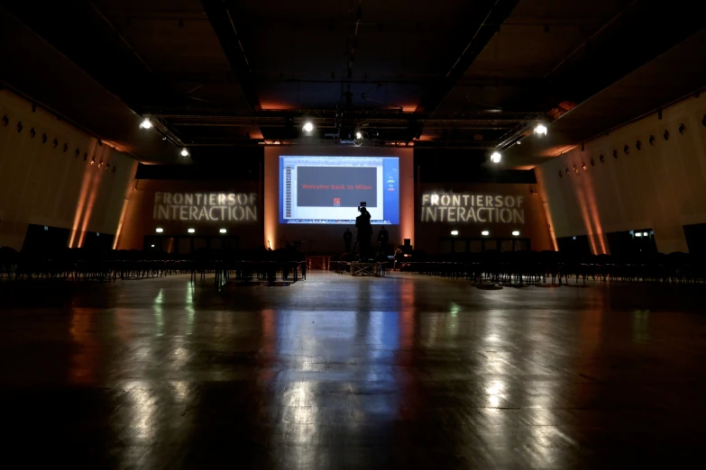 a dimly lit room containing many chairs and a projection screen