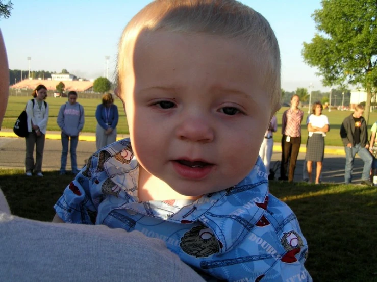 a little boy looking at the camera while it is held by his owner