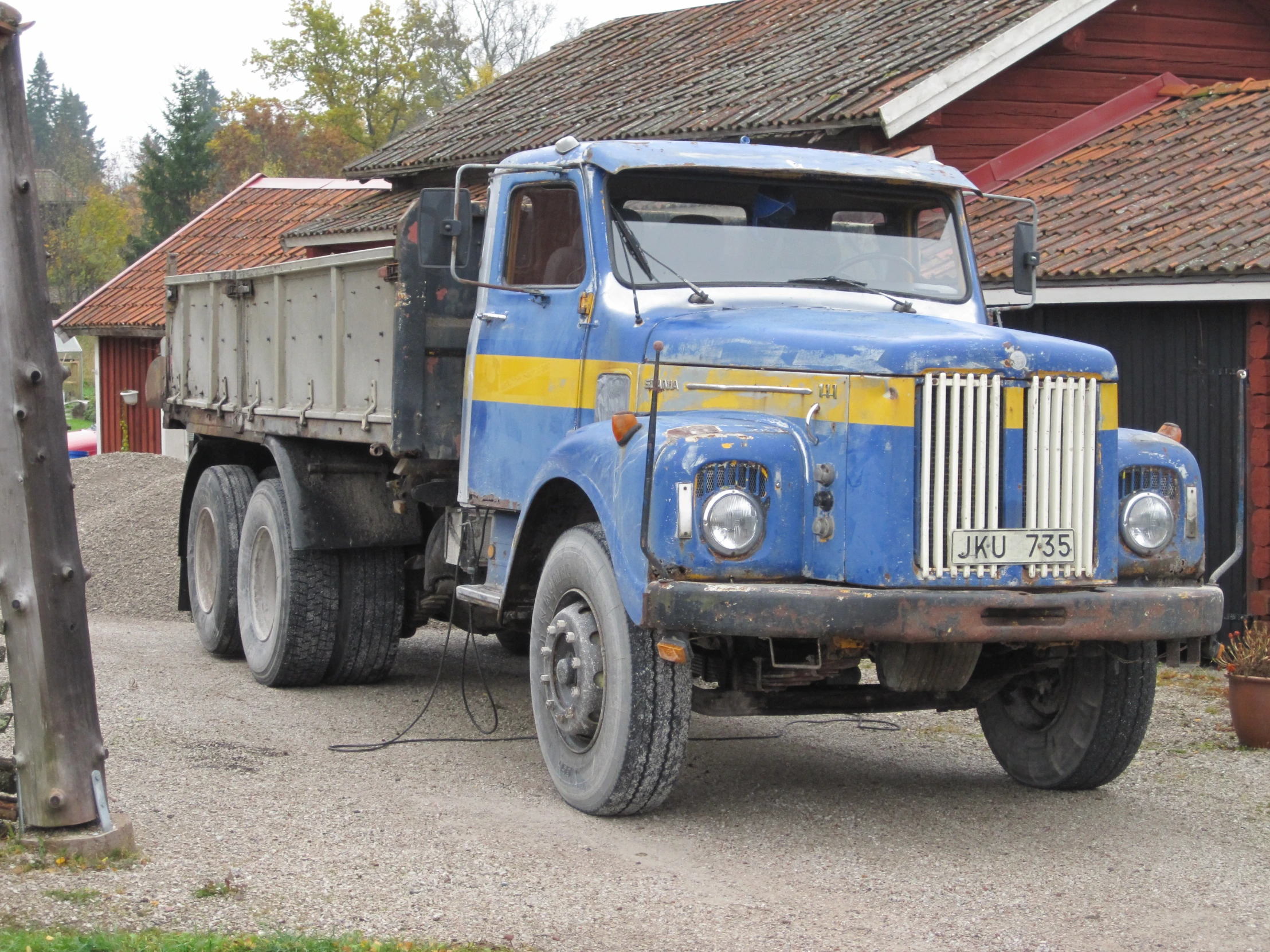 a blue dump truck parked on a gravel parking lot