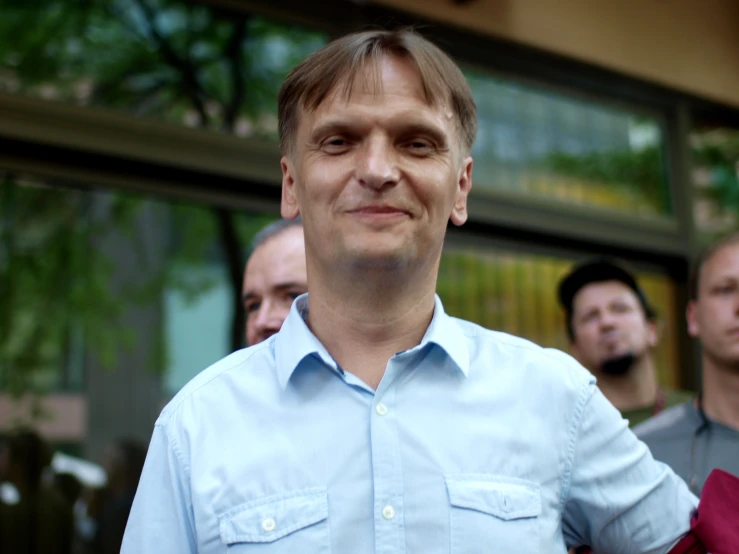 a man smiling and wearing a light blue on down