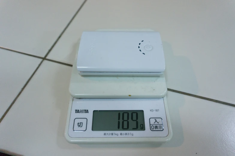a digital scale on a white tiled floor