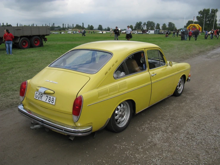 this old yellow car was parked on the grass