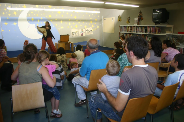 some people are sitting on chairs and are listening to an animal show