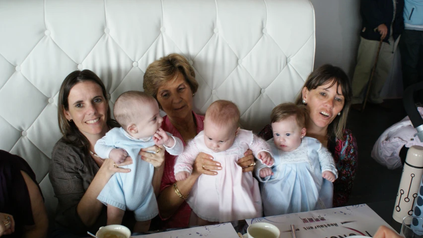 several women holding a baby and laughing at the camera