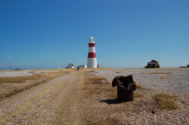 a black and white lighthouse sitting next to dirt road