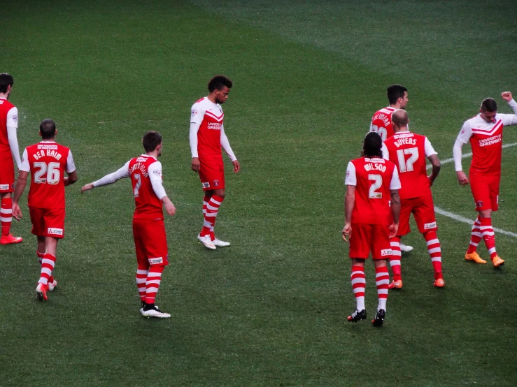 a group of men in red and white uniforms stand on a field