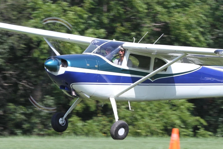 a small plane flying low above an orange cone