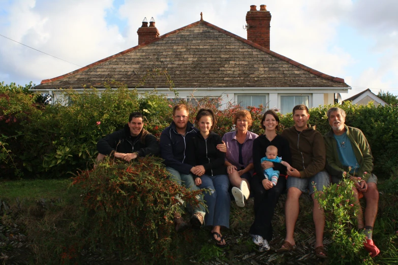 a group of people sitting on a fence in front of a house