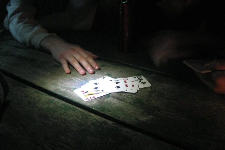 a person is playing in the dark with playing cards