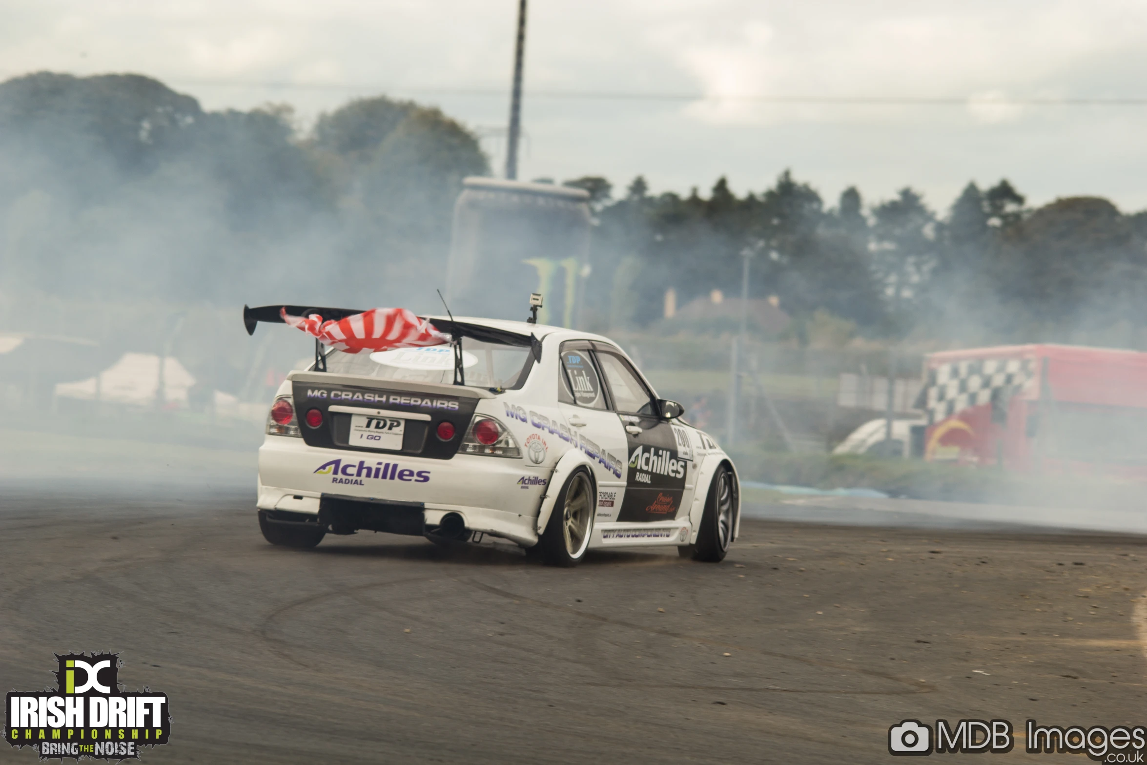 two cars driving on a track surrounded by smoke