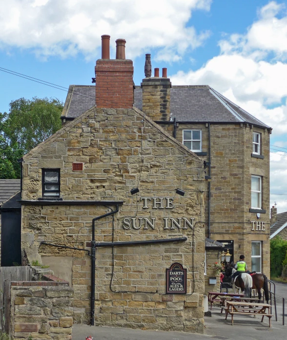 an old brick building with a horse drawn cart parked in front