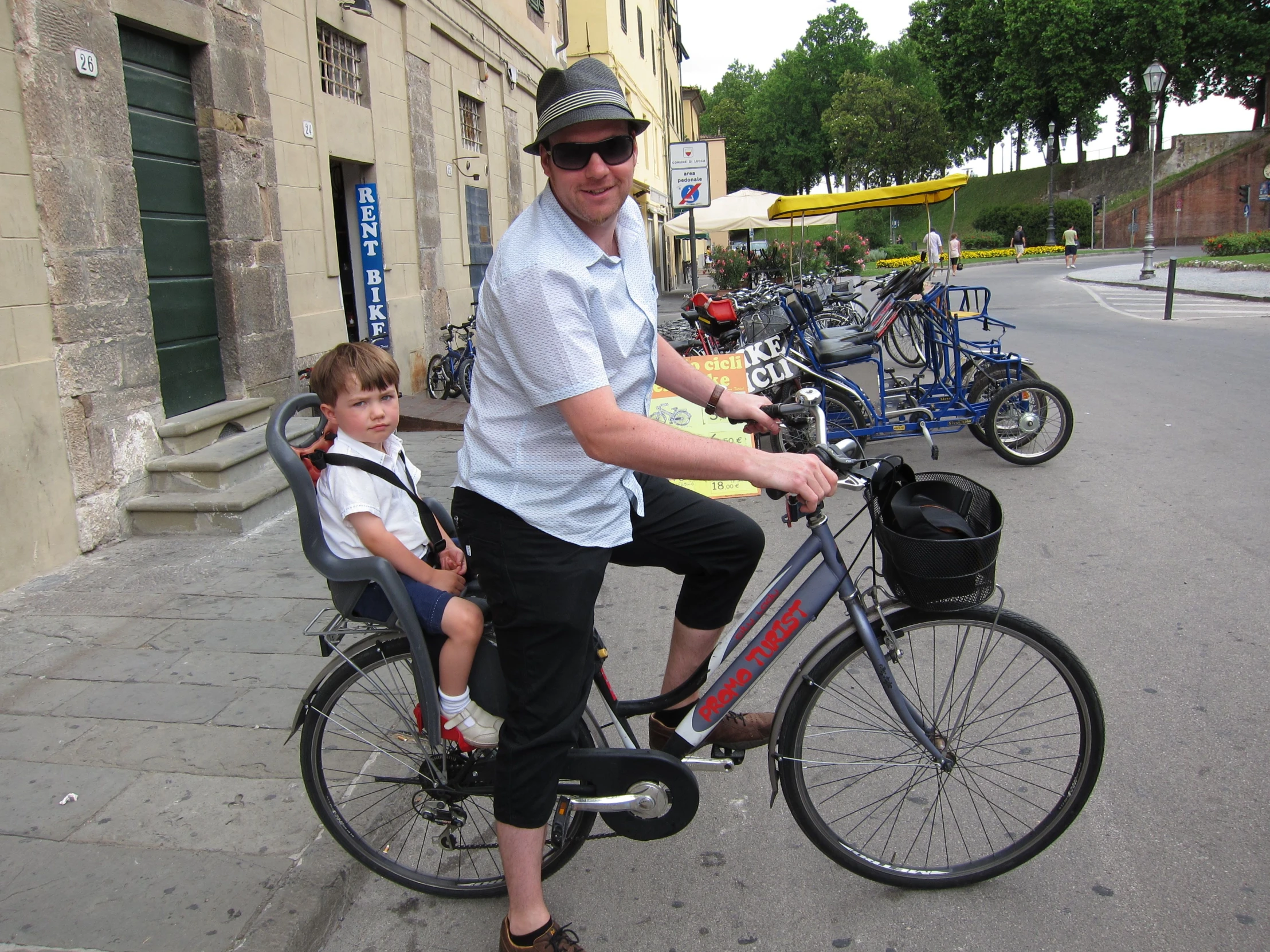 a man riding a bicycle with a boy sitting on the seat