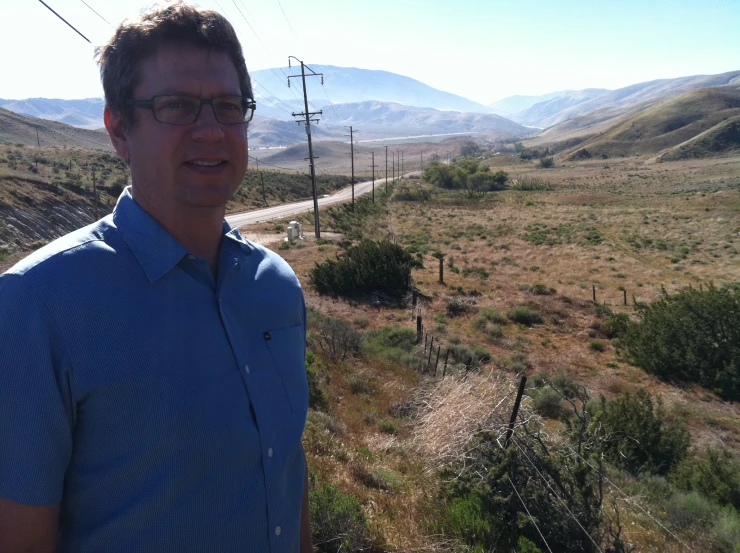 man in blue shirt and glasses standing in grassy area