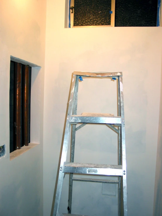 a ladder leaning against a wall in an unfinished bathroom