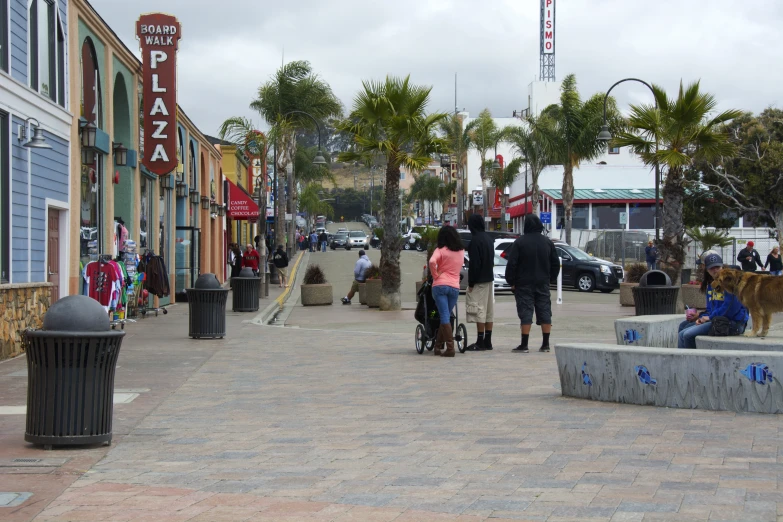 the people are walking down the street by the stores