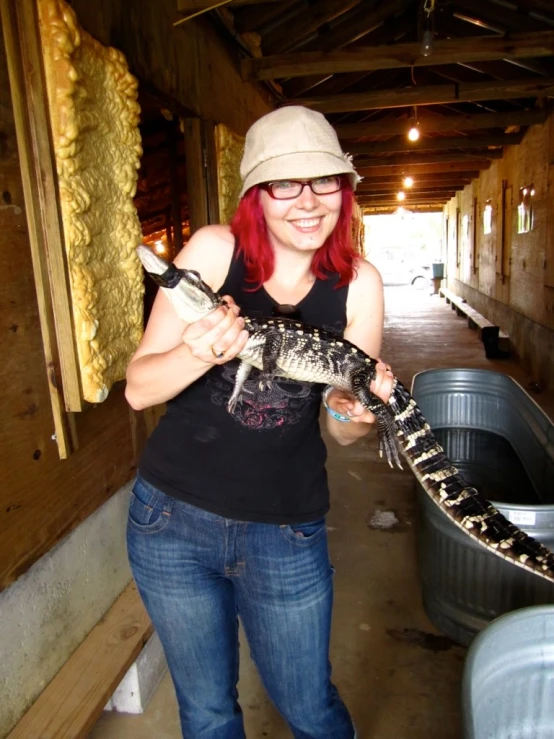 a woman holding a large alligator in an enclosed area