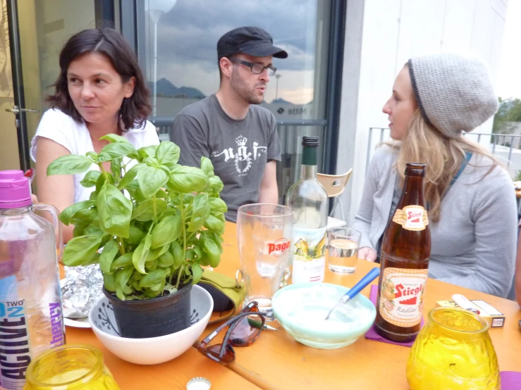 three people talking around a table with drinks and food