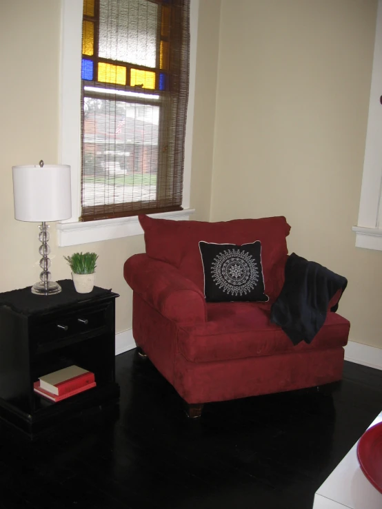 a red love seat and end table in front of window