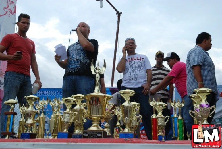 a group of men standing next to each other near trophies