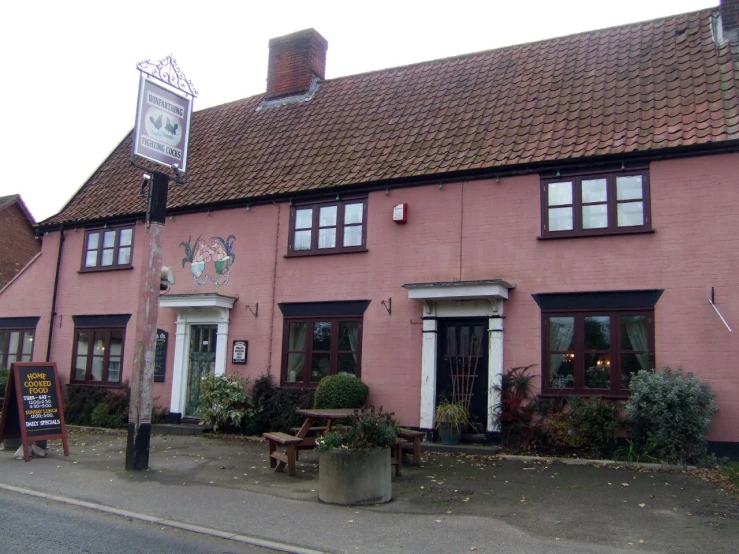 this is a pink and red building with a sign and a bench on the sidewalk