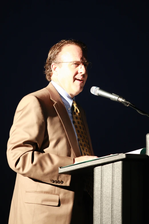 the man standing in front of a podium is giving a speech