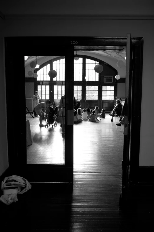 black and white pograph of people sitting in a gym