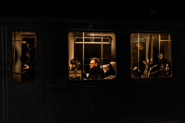 four people are sitting on the subway, all inside the same train