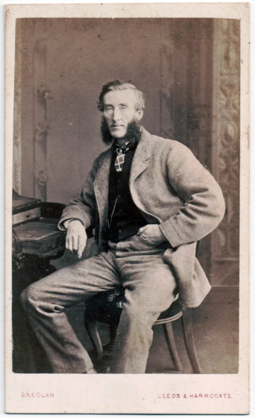 a man with a beard in a suit sitting on a chair