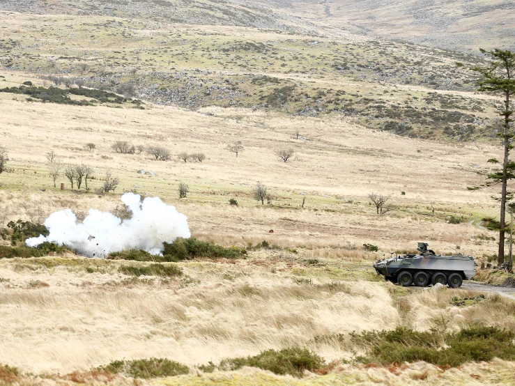 a army vehicle rolls out some white smoke