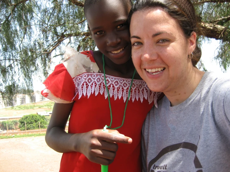 woman smiling in front of a tree holding onto a child