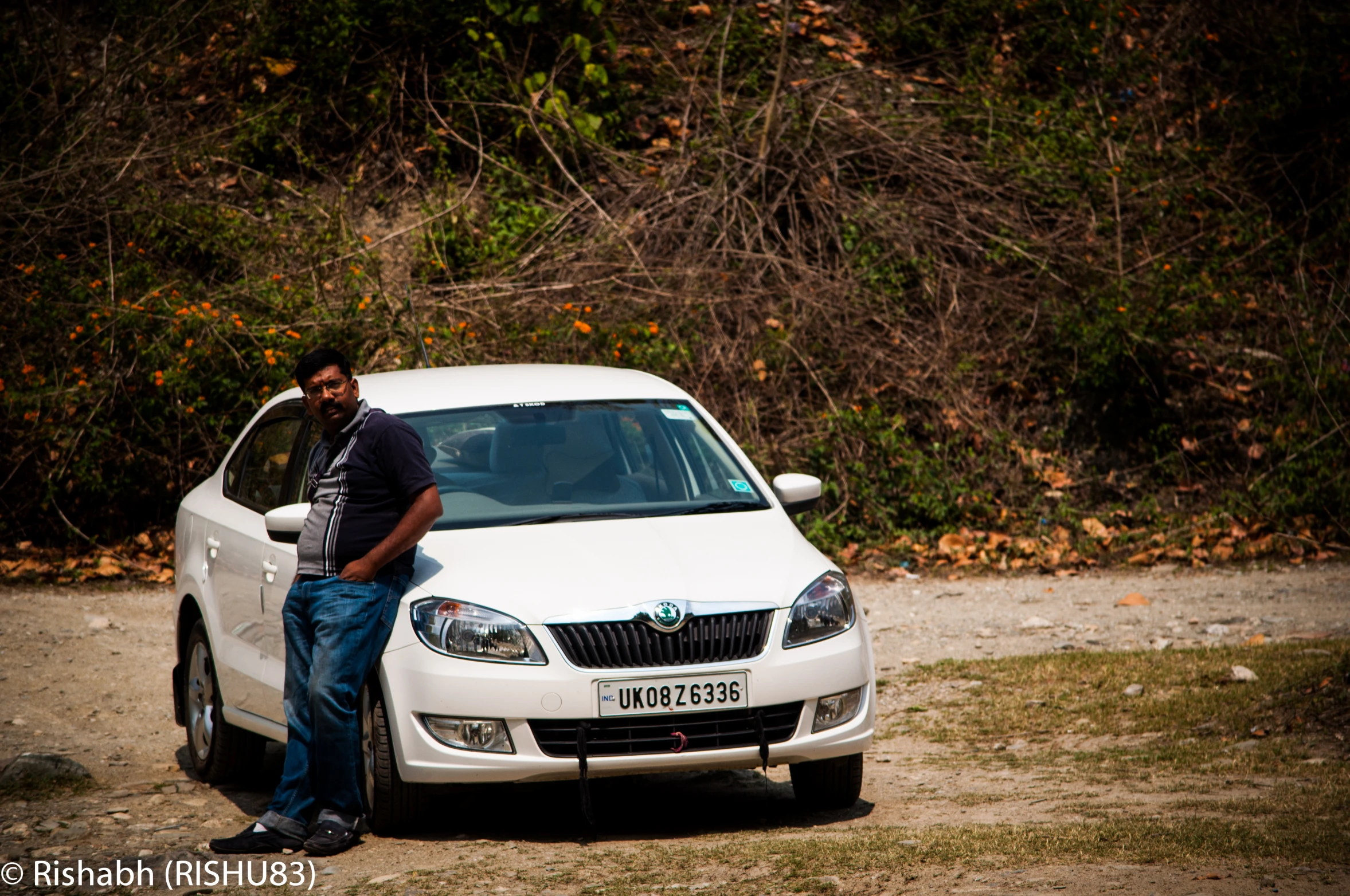 a man sits on the hood of a parked white car