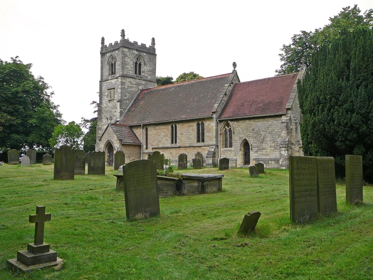 an old church that has a graveyard and green grass around it