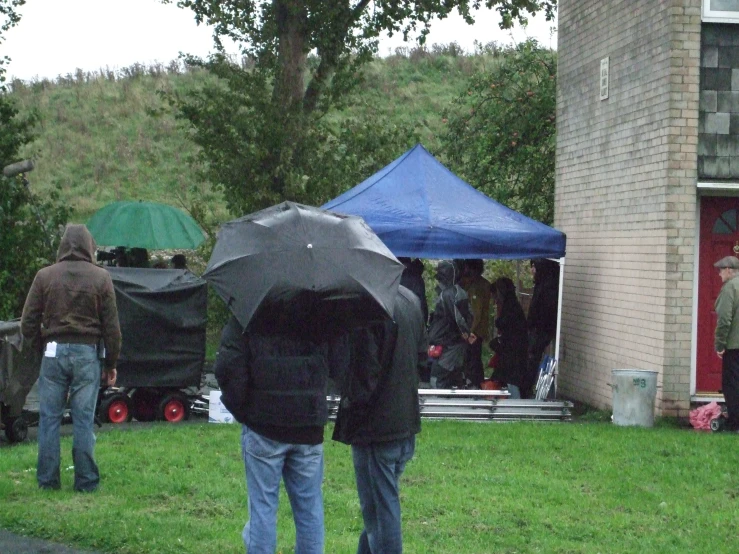 people holding umbrellas in a yard on a rainy day