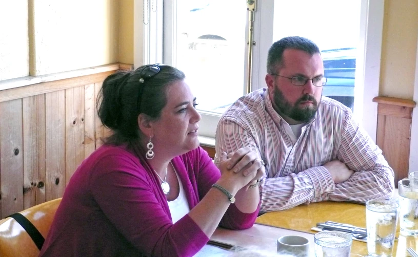 a man and a woman sitting at a table with a phone