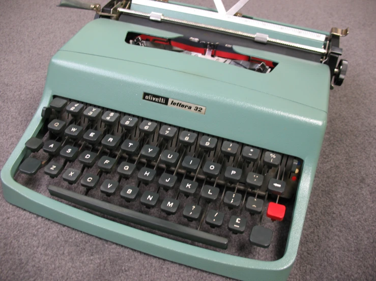 a vintage green typewriter on top of grey carpet