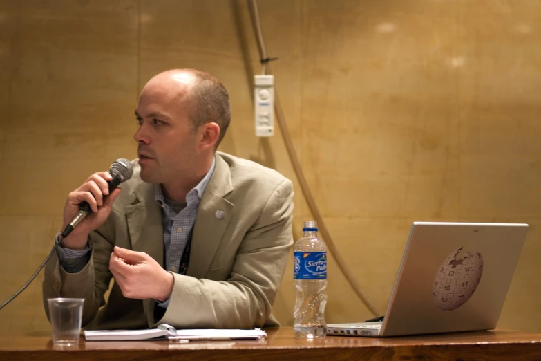 the man is sitting down at a desk with a microphone