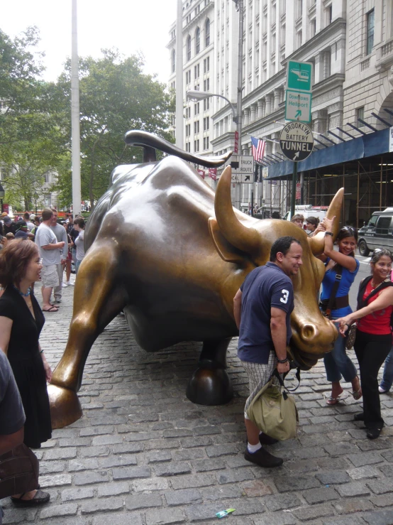 people standing around in front of a large bull statue