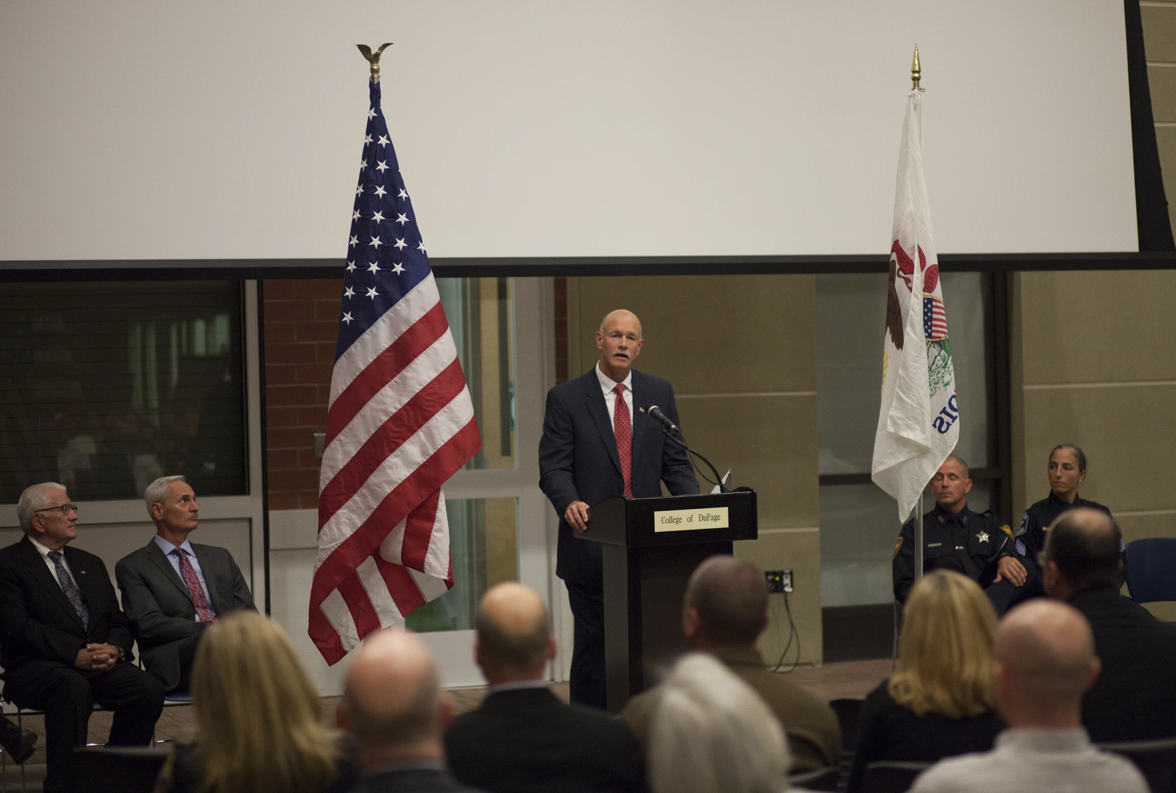 a man standing at a podium next to flags