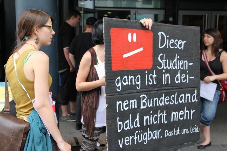 woman holding up a black sign with two white faces