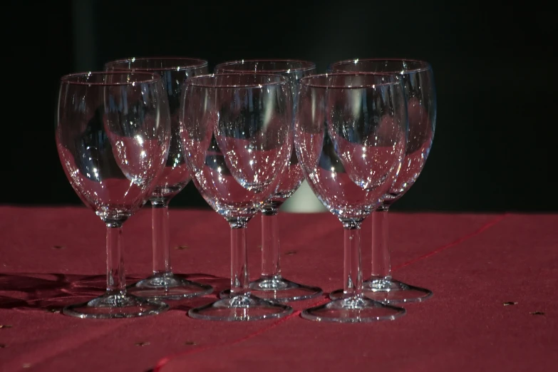 a red table with four glasses and a white vase in it