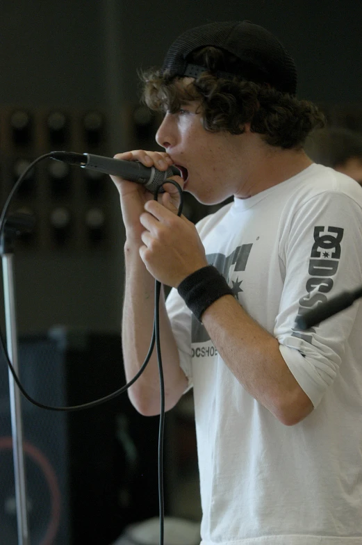 the boy is singing while standing near a microphone